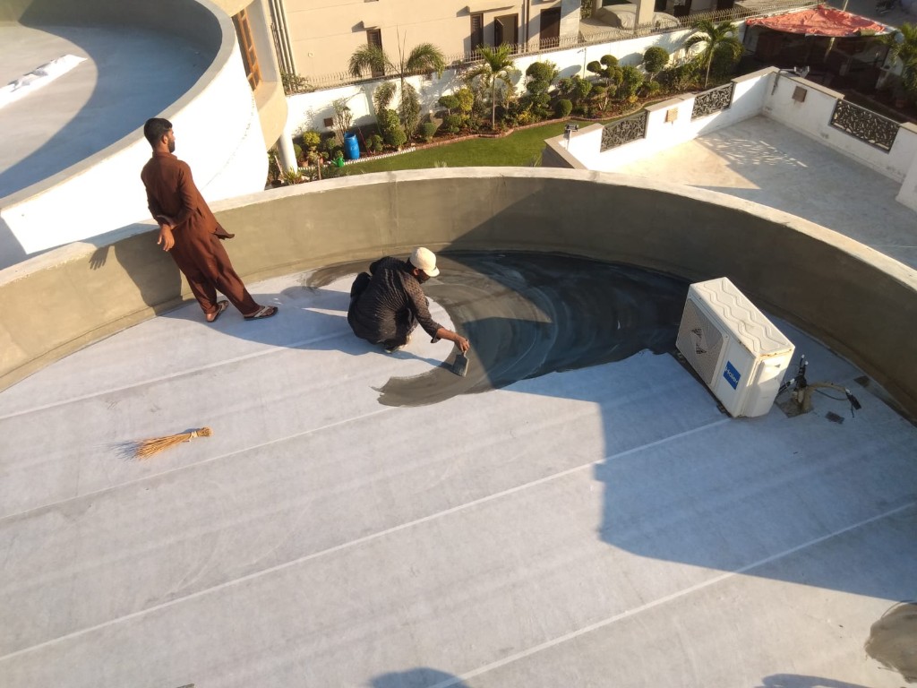 Technician applying liquid chemical coating over reinforcing fabric on a flat roof